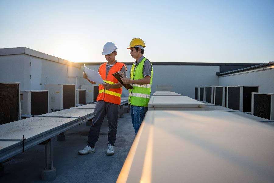 An image of 2 individuals in construction vests on-site, reviewing paperwork.