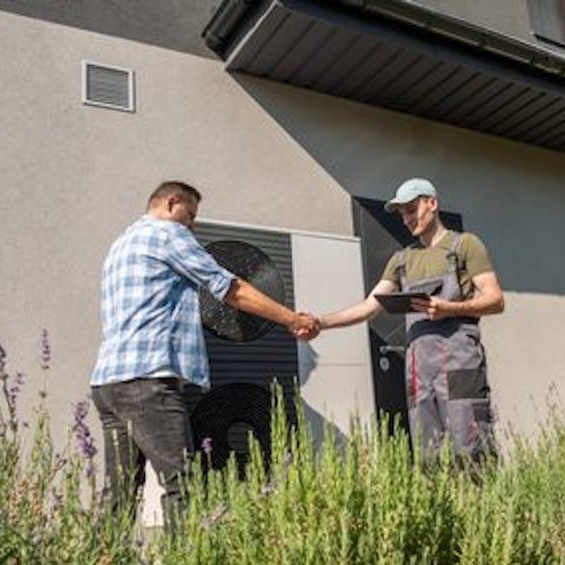 HVAC contractor shaking the hand of client standing outside of the home near the air conditioner unit